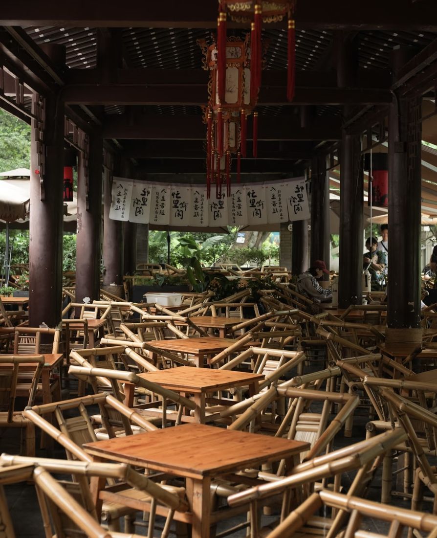 Bamboo chairs and tables inside Heming Teahouse, with red lanterns and calligraphy banners overhead