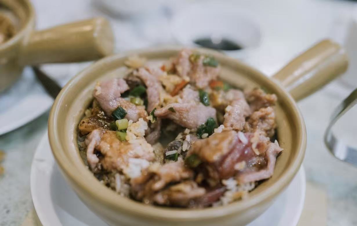 A Cantonese claypot rice dish with marinated meat and scallions, served in its traditional clay pot