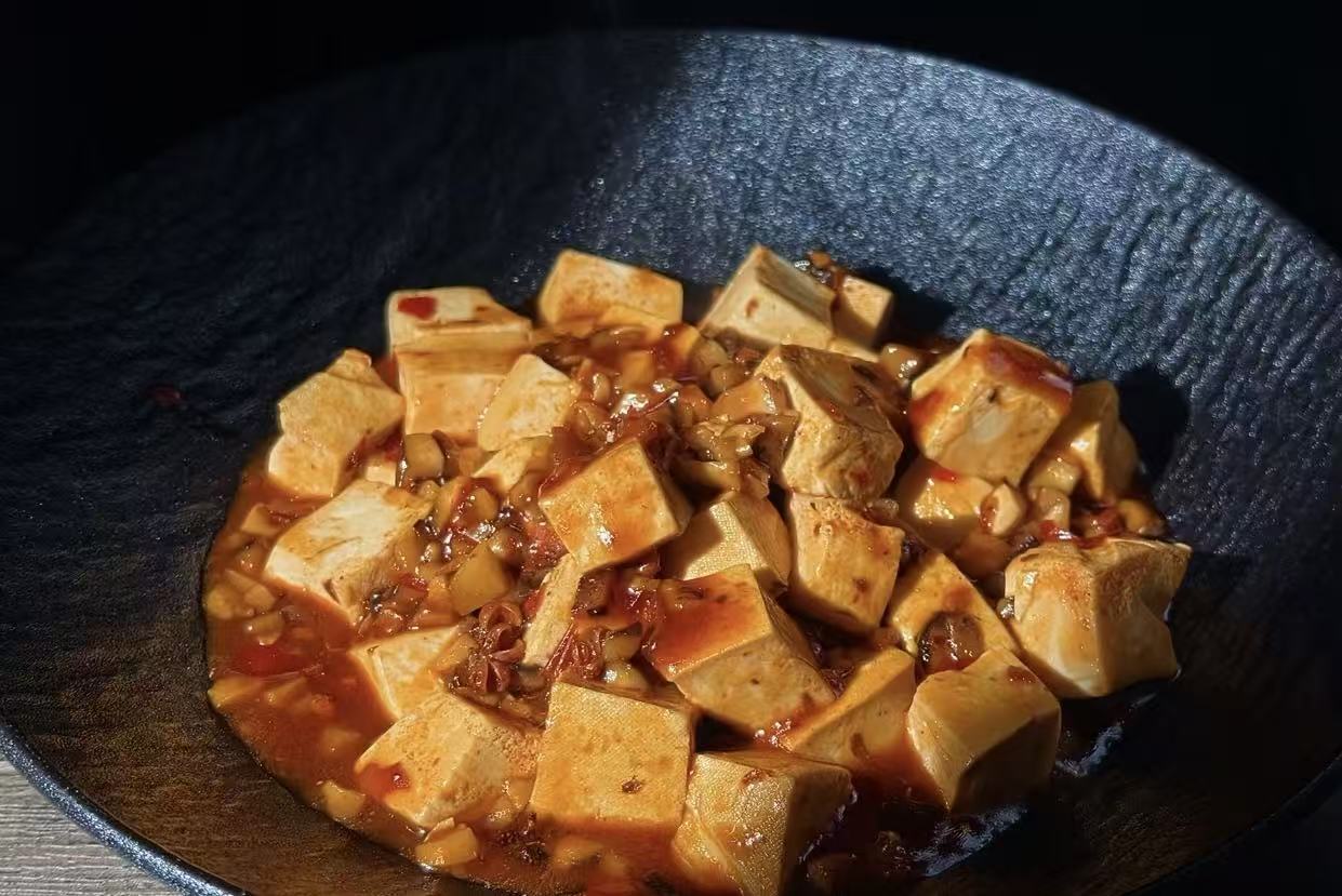 Mapo tofu cooking in a wok over high heat, a hallmark Sichuan dish